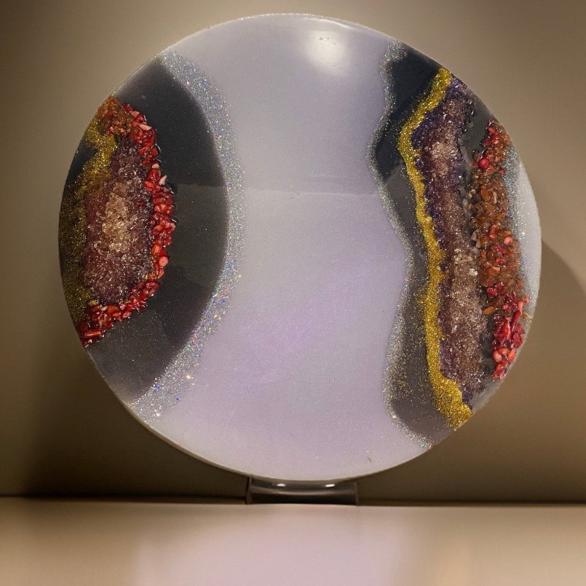 Round decorative geode art with multicolored mineral-like patterns on a light background.  This piece includes jasper  and amethyst stone 